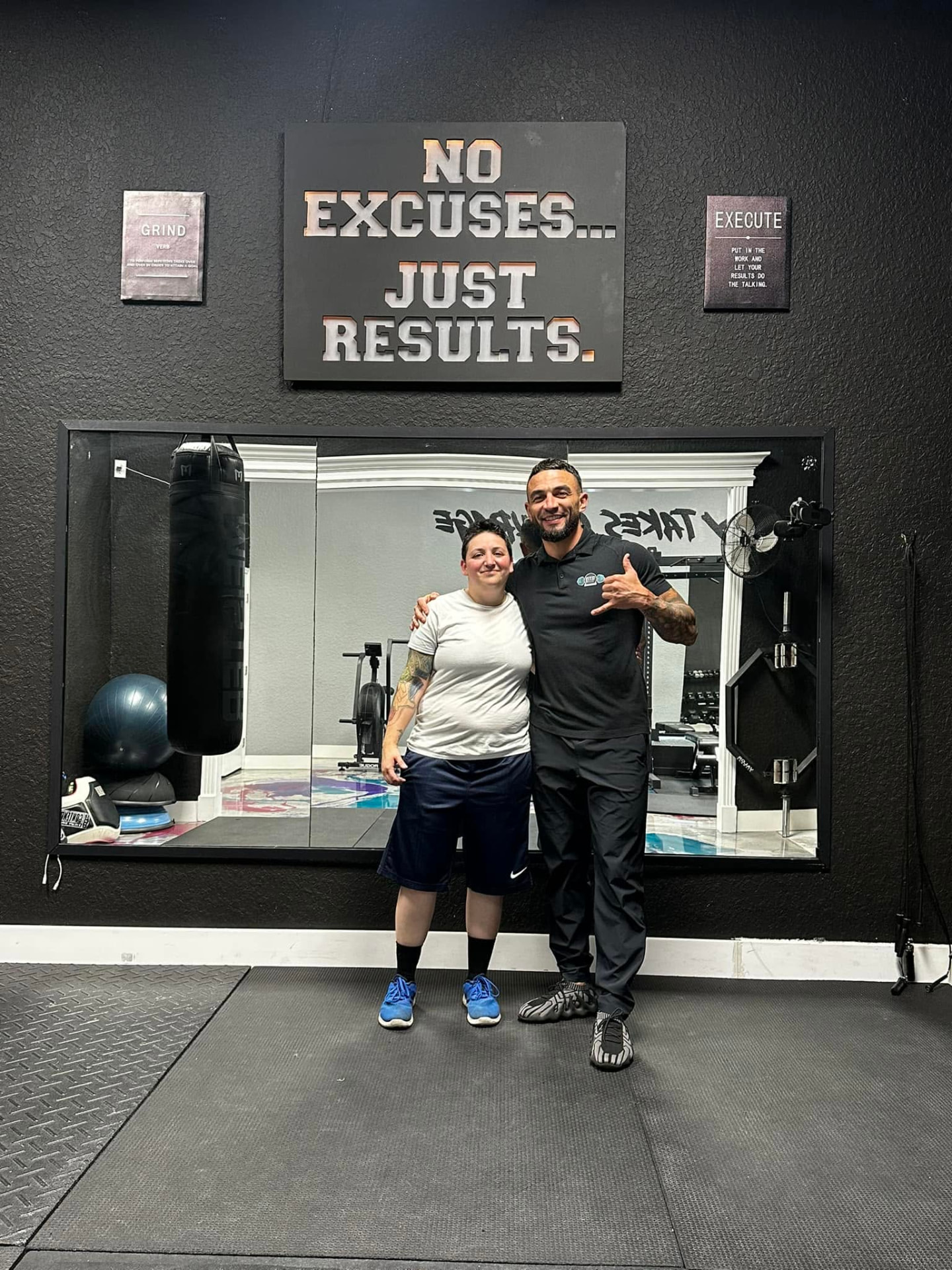 Member and Coach Jeremy under the No Excuses, Just Results wall