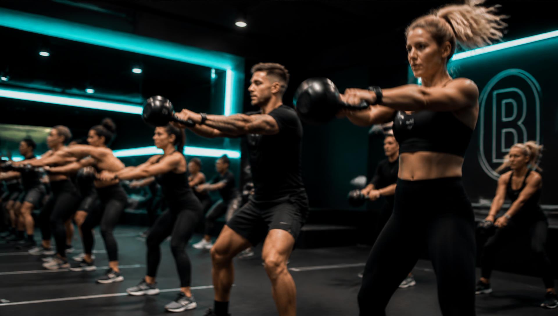 Members swinging kettlebells in a coach-led group class