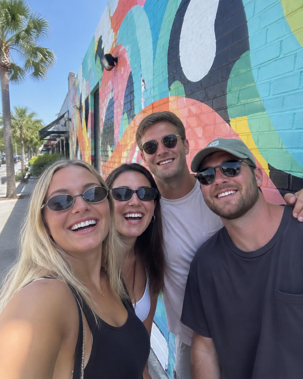 Friends taking a selfie in front of a colorful St. Pete mural